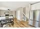 Open concept living area with hardwood floors, stainless steel refrigerator, and adjacent staircase at 9885 Thornbury Way, Highlands Ranch, CO 80129