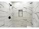 Modern walk-in shower featuring stylish marble-patterned tile and sleek black fixtures for a luxurious experience at 9885 Thornbury Way, Highlands Ranch, CO 80129