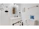 Well-lit bathroom features a white vanity with decorative black hardware, toilet, and neutral paint at 8438 Ames St, Arvada, CO 80003