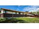 Back exterior view of a brick home with a grassy yard and a chimney at 9584 W Kentucky Ave, Lakewood, CO 80226