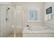 Bright bathroom with a glass enclosed shower, a soaking tub, and white subway tile at 5029 Silver Hare Ct, Castle Rock, CO 80104