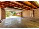 View of an open garage with a concrete floor, block walls, and an exposed wood beam ceiling at 10841 Montview Blvd, Aurora, CO 80010