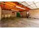 Spacious garage with exposed wood beams, concrete block walls, storage shelves and lawn equipment at 10841 Montview Blvd, Aurora, CO 80010