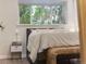 Close up of a charming bedroom nook featuring a comfortable bed and a woven bench, creating a cozy retreat with natural light at 1103 S Monaco Pkwy, Denver, CO 80224