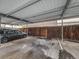 Covered carport parking area with a car, wooden fence and overhead metal roof at 1103 S Monaco Pkwy, Denver, CO 80224