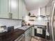 Stylish kitchen featuring sleek, light green cabinetry and stainless-steel appliances, creating a modern and functional cooking space at 1103 S Monaco Pkwy, Denver, CO 80224