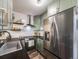A well-lit kitchen showcasing light green cabinets paired with stainless-steel appliances, exuding a contemporary and clean aesthetic at 1103 S Monaco Pkwy, Denver, CO 80224