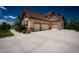 Spacious three-car garage and wide driveway complemented by landscaping and stone accents at 19735 Knights Xing, Monument, CO 80132