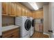 Functional laundry room with a sink, modern washer and dryer, wooden cabinets, and granite countertops at 19735 Knights Xing, Monument, CO 80132