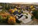 Aerial view of a large grey house with an attached garage, surrounded by lush trees in autumn colors at 5790 Fox Run Ct, Parker, CO 80134