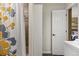 Bright bathroom featuring a floral shower curtain and a glimpse into the bedroom with bed and shelves at 5790 Fox Run Ct, Parker, CO 80134