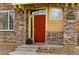 Inviting red front door with stone accents and decorative lights, creating a warm and welcoming entrance at 9980 W Jewell Ave # B, Lakewood, CO 80232