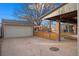 View of backyard featuring garage, wooden fence, concrete patio, and covered porch with brick pillars at 1545 Locust St, Denver, CO 80220