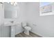 Clean half bathroom with white fixtures, a pedestal sink, a toilet, and a single window at 16618 W 92Nd Pl, Arvada, CO 80007