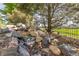 A serene backyard features a rock waterfall, lush greenery, and tranquil setting at 27565 E Nova Pl, Aurora, CO 80016