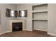 Close-up of a fireplace with light tile surround, built-in shelves, and window views at 9025 W 79Th Way # D, Arvada, CO 80005