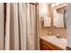 Bathroom with a shower behind a white curtain, wood cabinets and a white sink at 10109 W Fremont Ave, Littleton, CO 80127