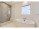 Modern bathroom featuring a soaking tub, glass shower, and neutral tile flooring at 231 Leafy Aster Ln, Castle Rock, CO 80104