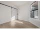 Bright bedroom featuring light wood floors, white walls, a barn door, and a window offering natural light at 561 Cherokee St, Denver, CO 80204