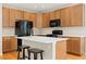 Kitchen with oak cabinets, white countertops, black appliances, and a central island with stool seating at 6520 S Newcastle Way, Aurora, CO 80016