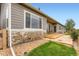 Back exterior of the home featuring a patio, stone accents, green grass and beautiful plants at 2716 Dundee Pl, Erie, CO 80516