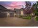 Inviting home exterior with a two-car garage, stone accents, and a beautifully lit driveway at dusk at 2716 Dundee Pl, Erie, CO 80516