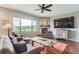 Cozy living room with brick fireplace, view of the outdoors, and ceiling fan at 2716 Dundee Pl, Erie, CO 80516