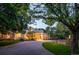 Modern home with a long driveway, lush landscaping, and warm lighting at 52 Sedgwick Dr, Cherry Hills Village, CO 80113