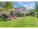 Expansive backyard with a brick patio, a fire pit, a deck, and lush greenery, perfect for outdoor living and entertainment at 16563 E Kansas Pl, Aurora, CO 80017