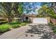 Charming home with a well-maintained lawn, mature trees, and a paved driveway leading to a two-car garage at 16563 E Kansas Pl, Aurora, CO 80017