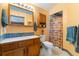 A well-lit bathroom featuring a wooden vanity, white sink, and cabinet space above the toilet and a patterned shower curtain at 4390 S Sheridan Blvd, Littleton, CO 80123