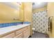 A bright bathroom with a white countertop, light wood vanity, and shower with green palm tree curtain at 4390 S Sheridan Blvd, Littleton, CO 80123