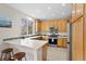 Bright kitchen with wood cabinets, stainless steel appliances, tile backsplash, and breakfast bar at 9864 S Garland Ct, Littleton, CO 80127