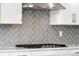 Close-up of gas range with gray herringbone backsplash and white cabinets at 17214 W 94Th Ave, Arvada, CO 80007