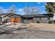 Ranch home with modern gray exterior, wood garage door and landscaping at 9163 W 75Th Cir, Arvada, CO 80005