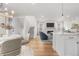 Open-concept view of living room with fireplace and flat screen TV, hardwood floors, and a view into the kitchen at 8028 Williams Fork Ave, Littleton, CO 80125
