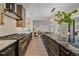 Modern kitchen featuring stainless steel appliances, marble countertops, an island with seating and views of the adjacent living room at 805 Elm St, Denver, CO 80220