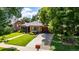 Charming brick home with a manicured front lawn, mature trees, and a classic driveway leading to a garage at 1635 Poplar St, Denver, CO 80220