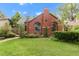 Brick home with chimney, turret entrance, arched windows, well-kept lawn, and mature landscaping at 1226 Dexter St, Denver, CO 80220