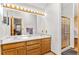Bright bathroom with double sinks, large mirror, vanity lighting and a glass shower at 10747 Timothys Dr, Conifer, CO 80433