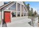 Close-up of the front of a mountain home featuring a red door, large windows, and a spacious deck at 10747 Timothys Dr, Conifer, CO 80433