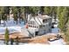 Charming mountain home with a striking red door, deck, and attached garage surrounded by a snow-covered landscape at 10747 Timothys Dr, Conifer, CO 80433