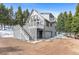 Gray mountain home with a deck, outdoor stairs, and attached garage surrounded by pine trees at 10747 Timothys Dr, Conifer, CO 80433
