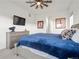 A large bedroom with a ceiling fan, gray dresser, and a luxurious blue bedspread at 5681 Water Avens Dr, Castle Rock, CO 80104
