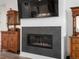 Close-up of modern gas fireplace with tile surround, flanked by antique wood cabinets at 5681 Water Avens Dr, Castle Rock, CO 80104