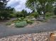 A beautiful landscaped garden with winding gravel paths, vibrant foliage, and tranquil seating areas at 1765 S Kline Way, Lakewood, CO 80232