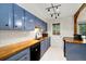 Modern kitchen with bright blue cabinetry, wooden countertops, and stainless steel appliances at 1765 S Kline Way, Lakewood, CO 80232