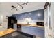 Modern kitchen featuring blue cabinets, butcher block countertops, and stainless-steel appliances at 1765 S Kline Way, Lakewood, CO 80232