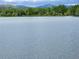 Scenic lake view with lush green trees and distant mountains under a cloudy sky at 1765 S Kline Way, Lakewood, CO 80232