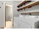 Functional laundry room with washer, dryer, and wooden shelving for storage at 1765 S Kline Way, Lakewood, CO 80232